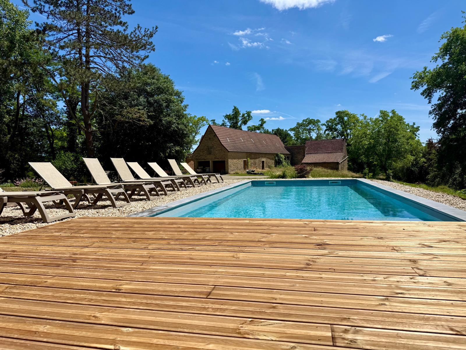 La piscine de La Casa Baccata, les transats et la grange en pierre