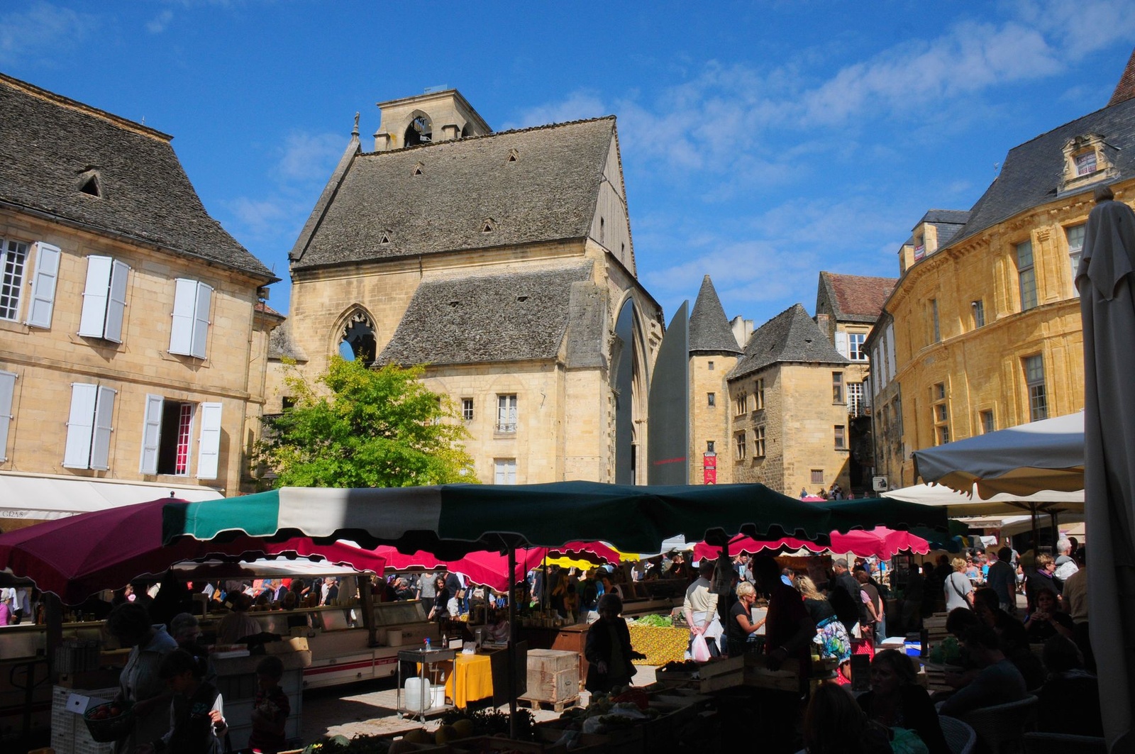 Les étals et les auvents du marché devant les façades de pierre de Sarlat