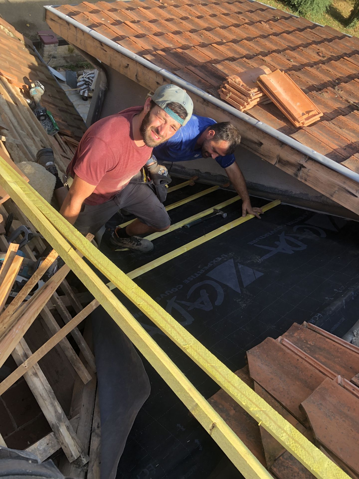 Deux personnes travaillent sur une partie de la toiture pendant la rénovation.